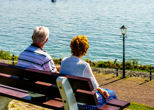 Elderly couple sitting on a bench looking out over the water